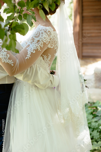 Bride and groom in green leaves  weddind background hugging photo