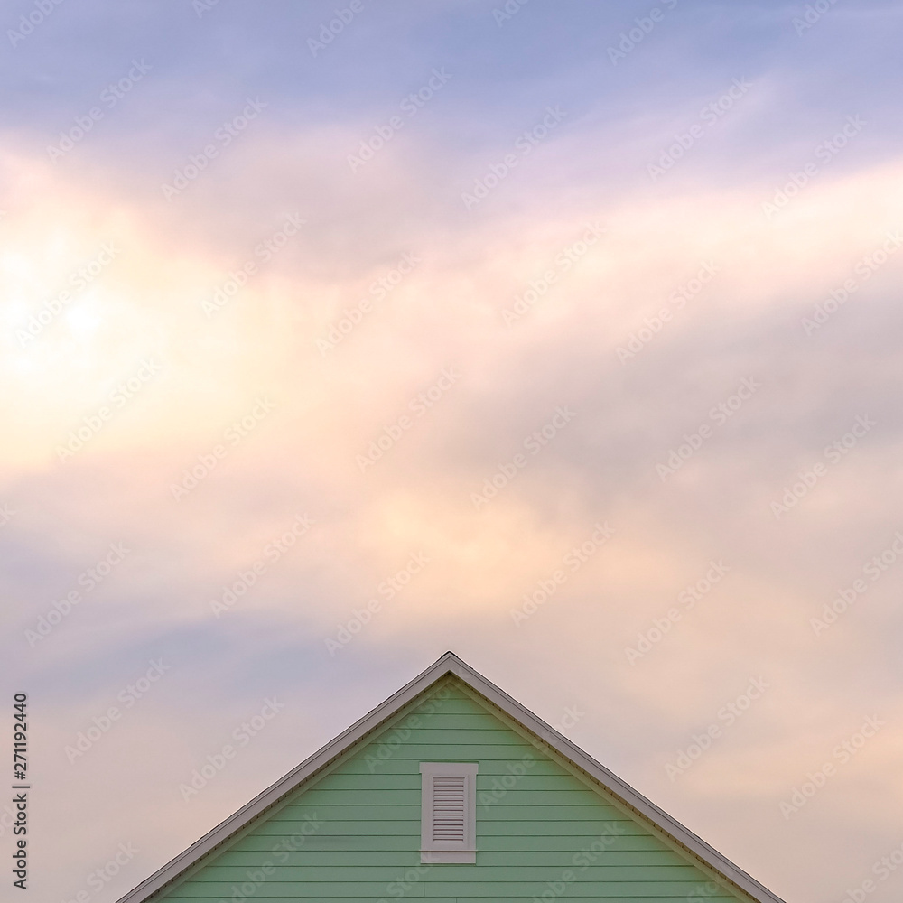 Square frame Top exterior of a house with view of the light green wall and gable vent