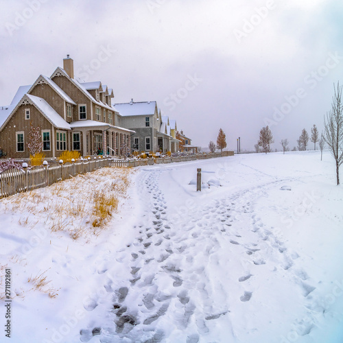Square Row of charming houses with snowy yards inside the wooden fences in winter