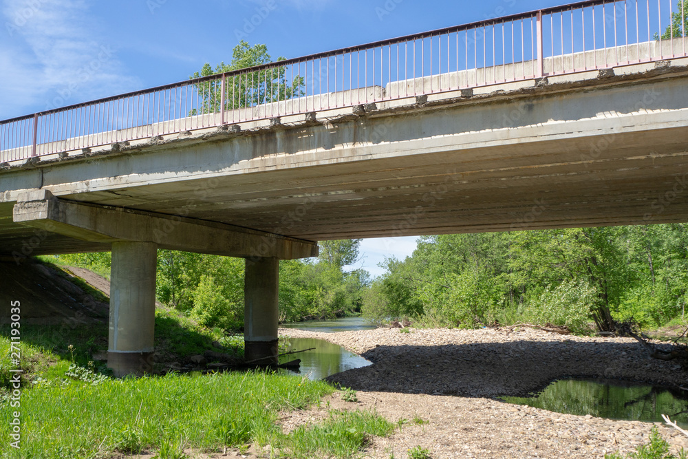 Reinforced concrete road bridge over the river. Close-up. Summer landscape.