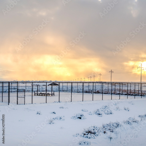 Square Tennis courts inside a chain link fence and blanketed with snow in winter © Jason