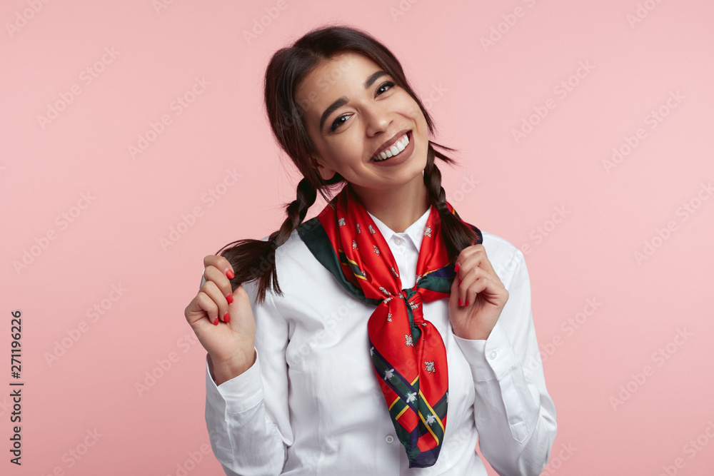 Attractive stylish girl with bright smile, wearing white shirt and stylish scarf, smiling against pink background Attractive stylish girl with bright smile, wearing white shirt and stylish scarf, smiling against pink background