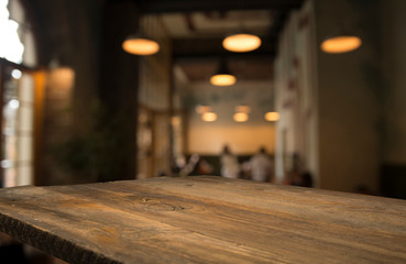 image of wooden table in front of abstract blurred background of resturant lights