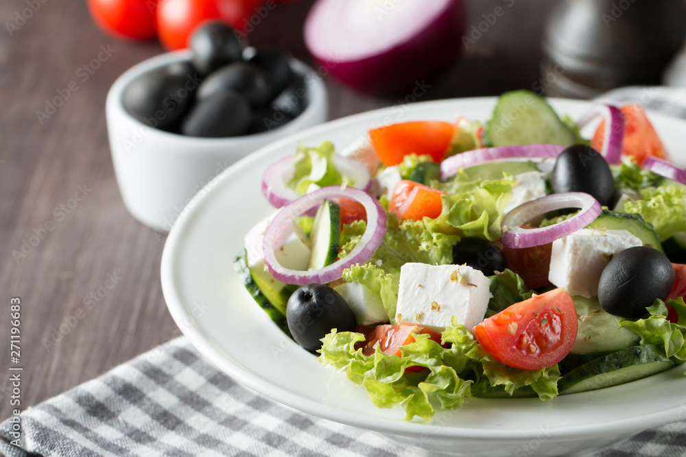 Fresh healthy salad with delicious ruccola, spinach, cabbage, arugula, feta cheese, red onion, cucumber, sesame seeds and cherry tomato on wooden background. Healthy and diet food concept.