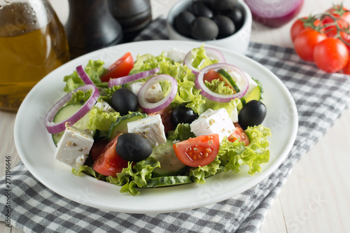 Fresh healthy salad with delicious ruccola, spinach, cabbage, arugula, feta cheese, red onion, cucumber, sesame seeds and cherry tomato on wooden background. Healthy and diet food concept.