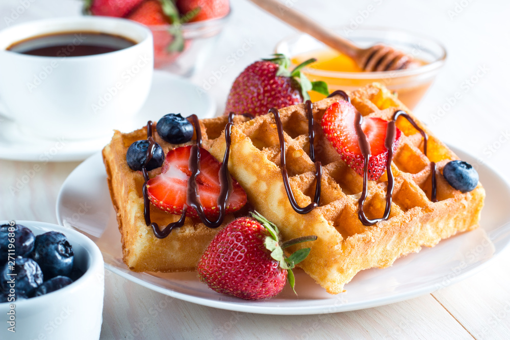 Fresh homemade food of berry Belgian waffles with honey, chocolate, strawberry, blueberry, maple syrup and cream. Healthy dessert breakfast concept with juice Fresh homemade food of berry Belgian waffles with honey, chocolate, strawberry, blueberry, maple syrup and cream. Healthy dessert breakfast concept with juice