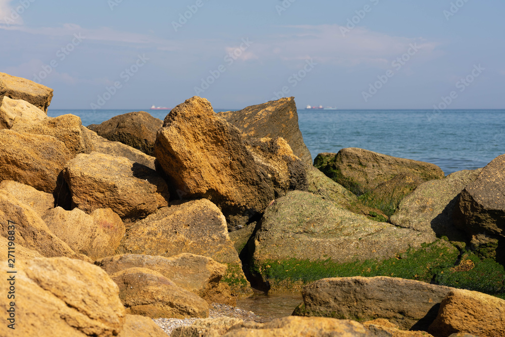 View of the Black Sea on a clear sunny day. On the shore, stones and sand, ships on the horizon. Blue sky and beautiful clouds. View of the Black Sea on a clear sunny day. On the shore, stones and sand, ships on the horizon. Blue sky and beautiful clouds.