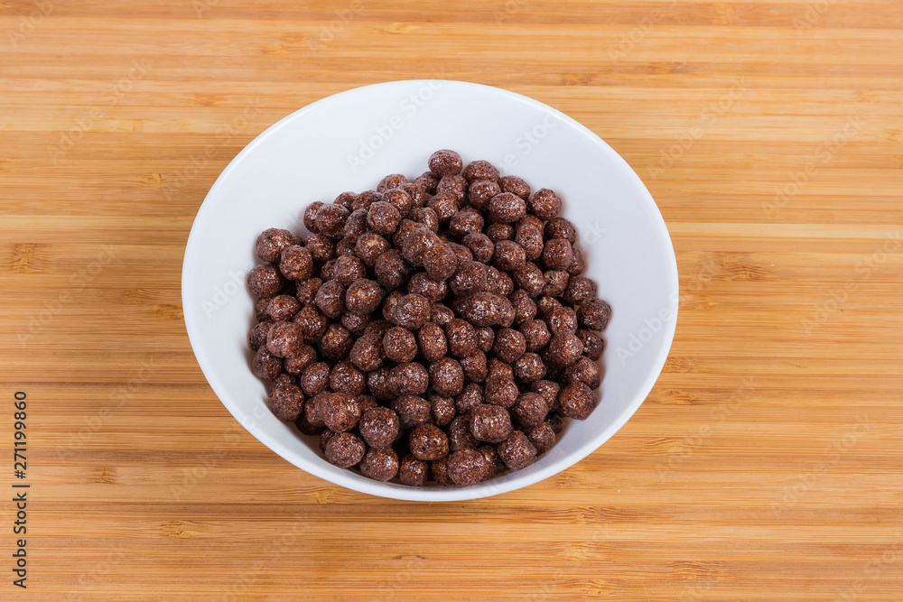Breakfast cereal chocolate balls in bowl on a wooden surface