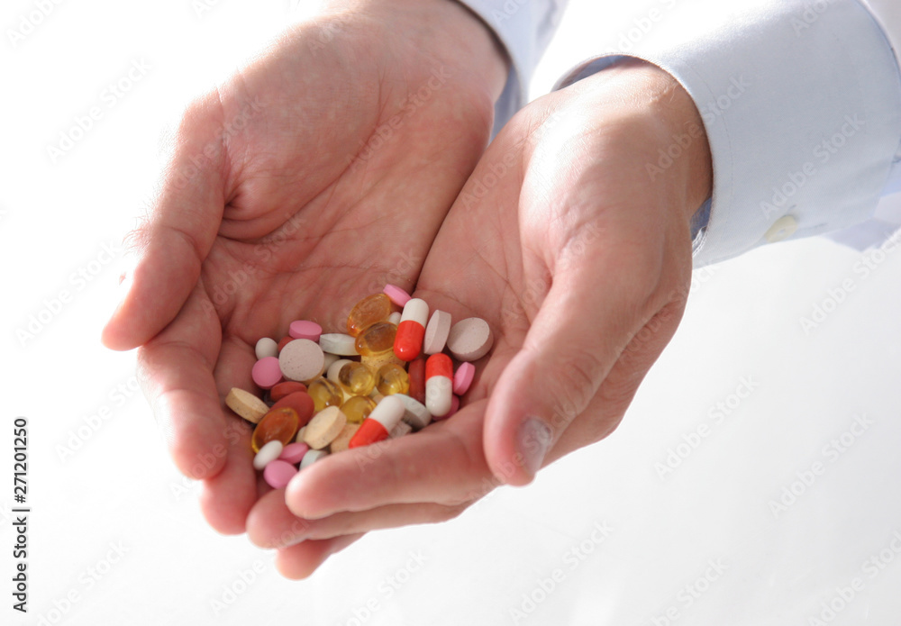 Male doctor holding a stack of many different pills Male doctor holding a stack of many different pills