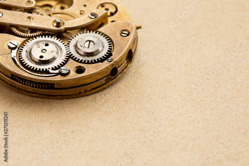 Antique pocket watch chronometer clockwork mechanism, cogs wheels transmition macro view. Shallow depth of field, selective focus. Aged paper textured background. Copy space photo