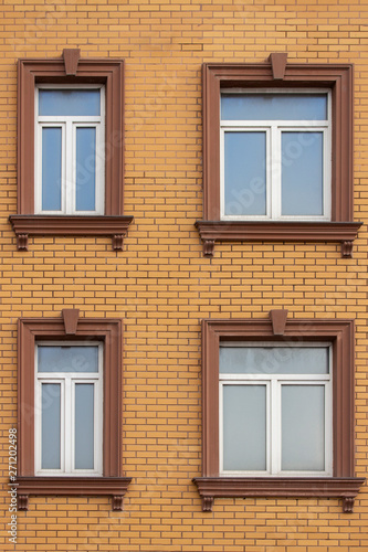 4 plastic windows in the brick house of yellow bricks. Beautiful windows with moldings and brown trim. Modern design of windows, construction of residential buildings © OlgaKorica