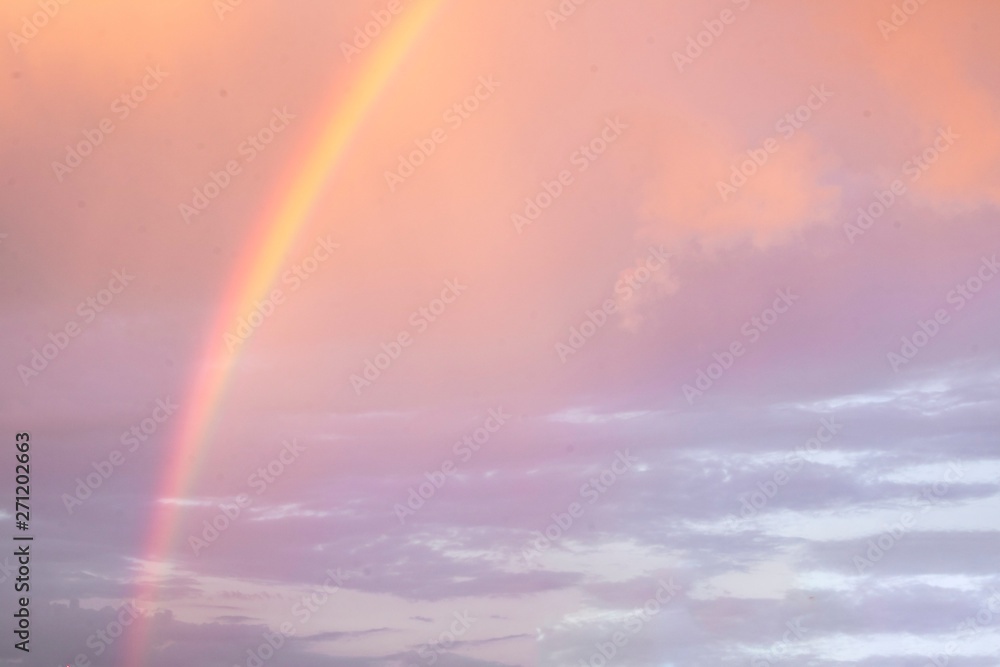 Bright beautiful rainbow on the background of coloured cloudy sry while sunset. Season, summer, phenomenon of nature