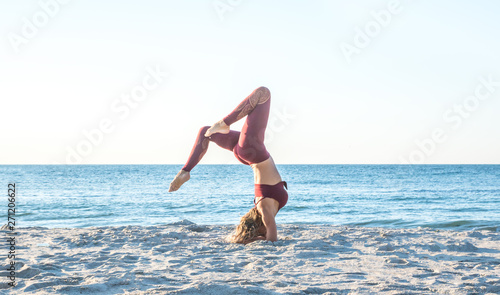 caucasian healthy adult woman with beautiful body doing yoga at sunrise on the beach, yoga poses © AlexR