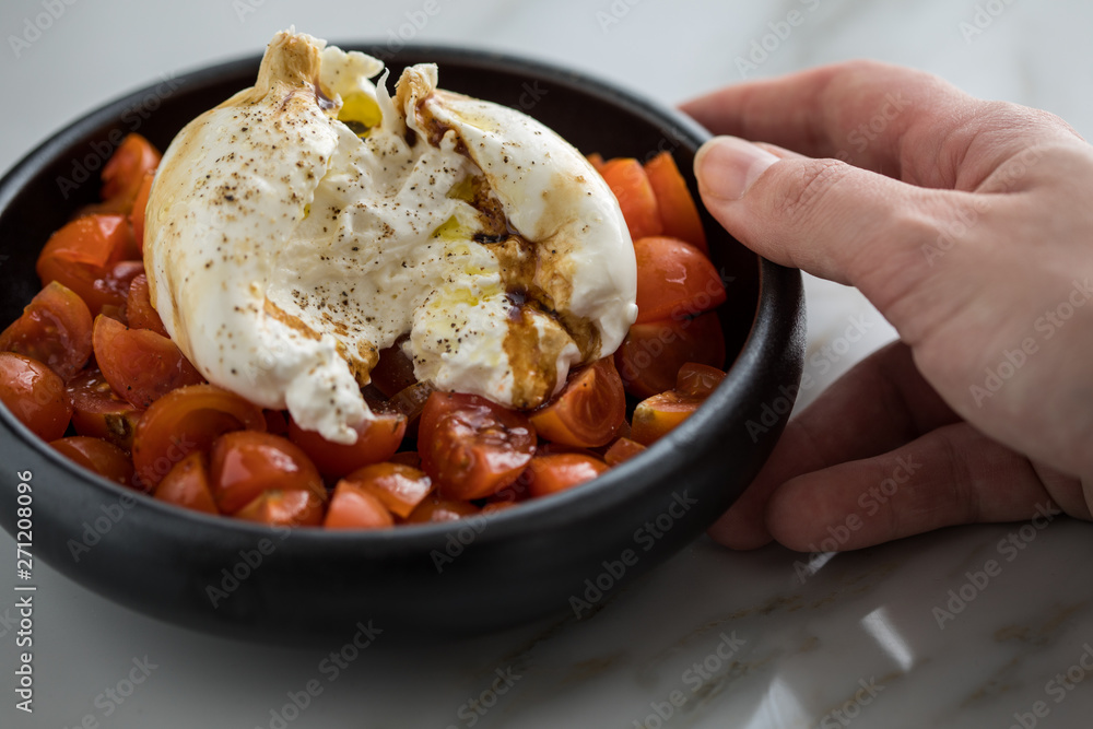 Frau isst Burrata Büffelmozzarella Kugel mit Tomaten, Olivenöl und Balsamico auf schwarzen Teller Frau isst Burrata Büffelmozzarella Kugel mit Tomaten, Olivenöl und Balsamico auf schwarzen Teller