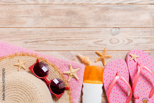 flip flops, straw hat, starfish, sunscreen bottle, body lotion spray on wooden background top view . flat lay summer beach sea accessories background, vaation concept photo