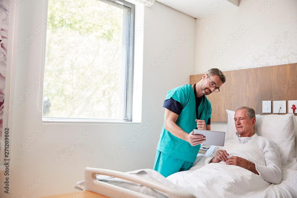 Fototapeta premium Surgeon With Digital Tablet Visiting Senior Male Patient In Hospital Bed In Geriatric Unit