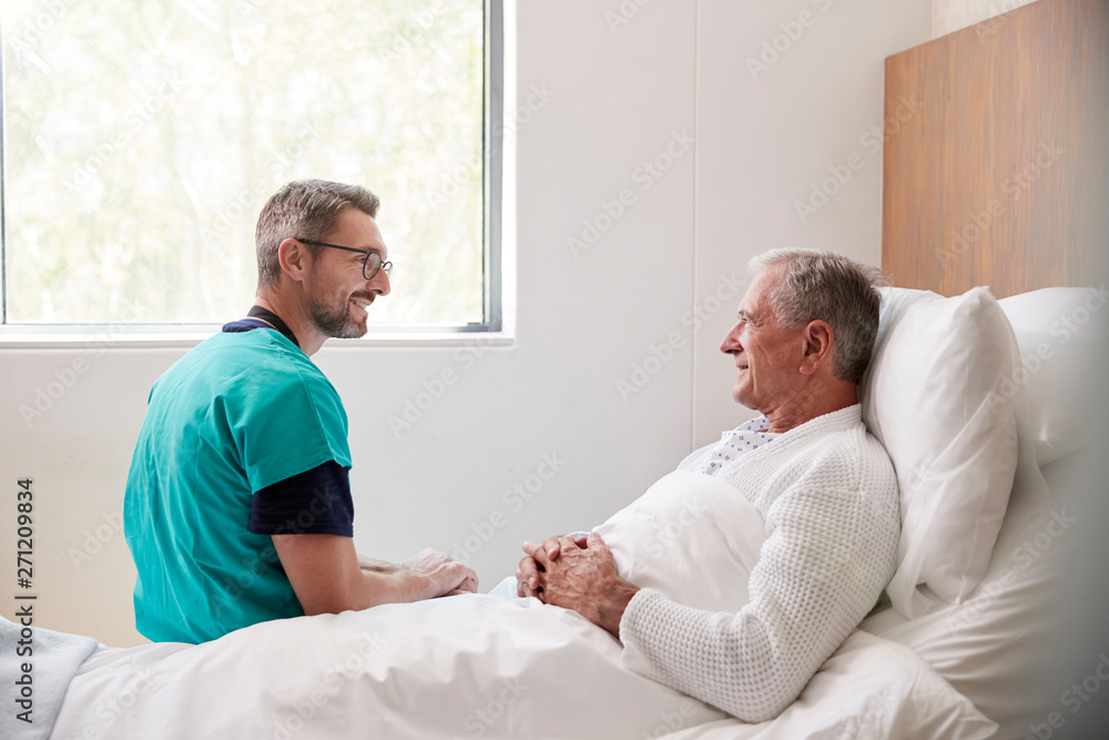 Surgeon Visiting And Talking With Senior Male Patient In Hospital Bed In Geriatric Unit Surgeon Visiting And Talking With Senior Male Patient In Hospital Bed In Geriatric Unit