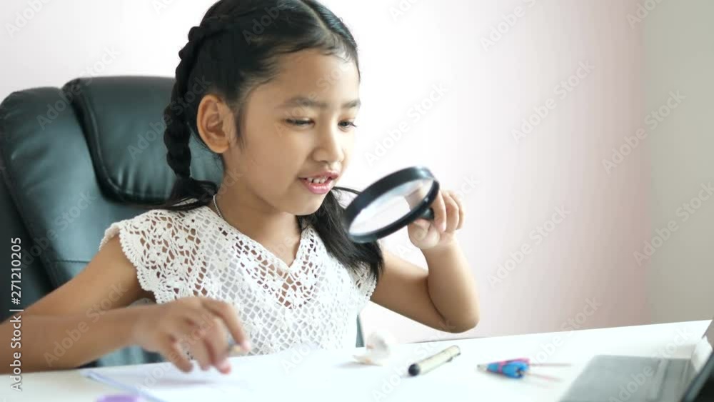 Little Asian girl using magnifier doing homework and smile with happiness for education concept select focus shallow depth of field Little Asian girl using magnifier doing homework and smile with happiness for education concept select focus shallow depth of field