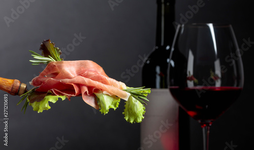 Prosciutto with rosemary and red wine on a dark background.