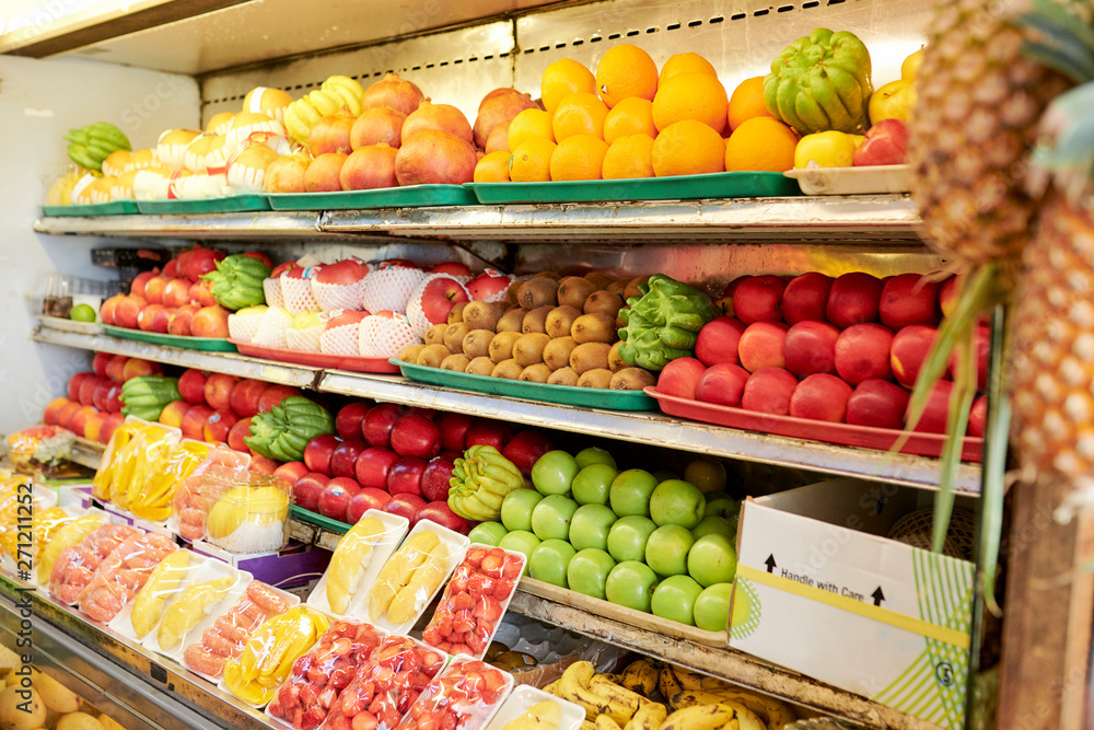 Shelves with delicious ripe colorful fruits and berries in supermarket