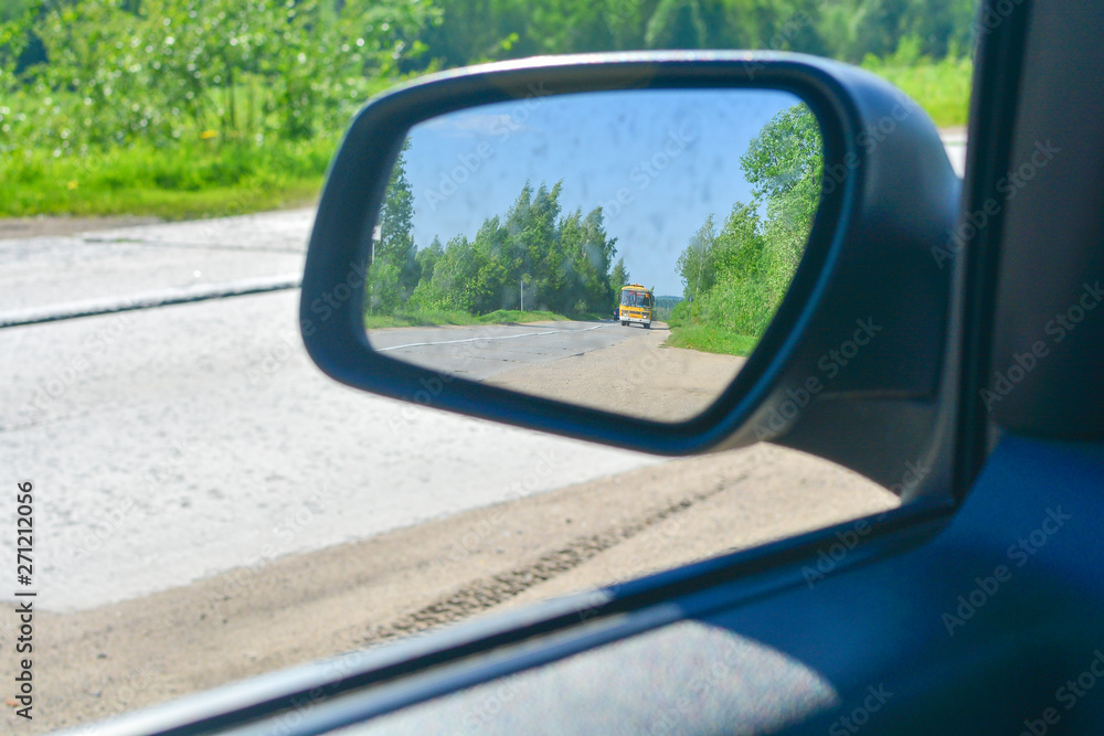 reflection of traffic in the left rear-view mirror on a sunny day.