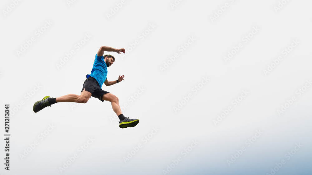 Athlete man running in the mountains during a jump in the sky