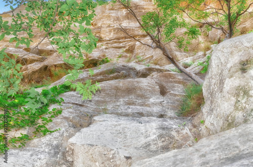 Climbing wall at the hillside of a rocky mountain. Carabiners ready to be used by the climbers. Somber zone. Natural sunlight of summer morning time. Soft focus. Climbing wall at the hillside of a rocky mountain. Carabiners ready to be used by the climbers. Somber zone. Natural sunlight of summer morning time. Soft focus.
