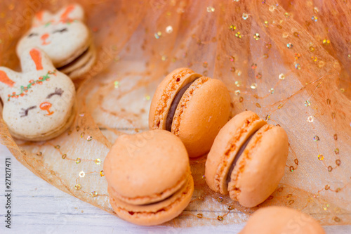 Orange macaroons with chocolate filling and Easter bunny macaroons, on orange tulle background photo