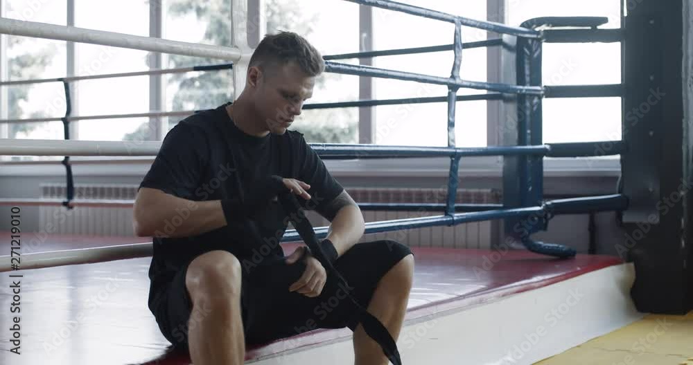 Man wraps his hands with boxing bandages, kickboxing training day in a gym, slow motion. Man wraps his hands with boxing bandages, kickboxing training day in a gym, slow motion.