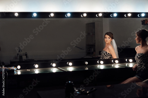 stylish gorgeous bride getting makeup in the luxury beauty saloon with big mirrors and light