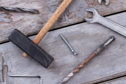 Construction tools on wooden background. Hammer, spanner, screws and drill bits on old wooden boards.