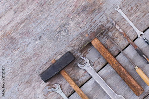 Set of carpenters tools on wooden background. Old hammer, spanners, screwdriver and drill bit. Space for text.