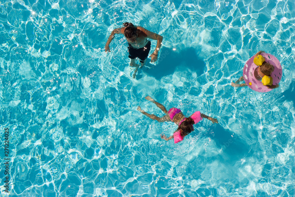 Aerial view of a father and his two kids in the pool, playing