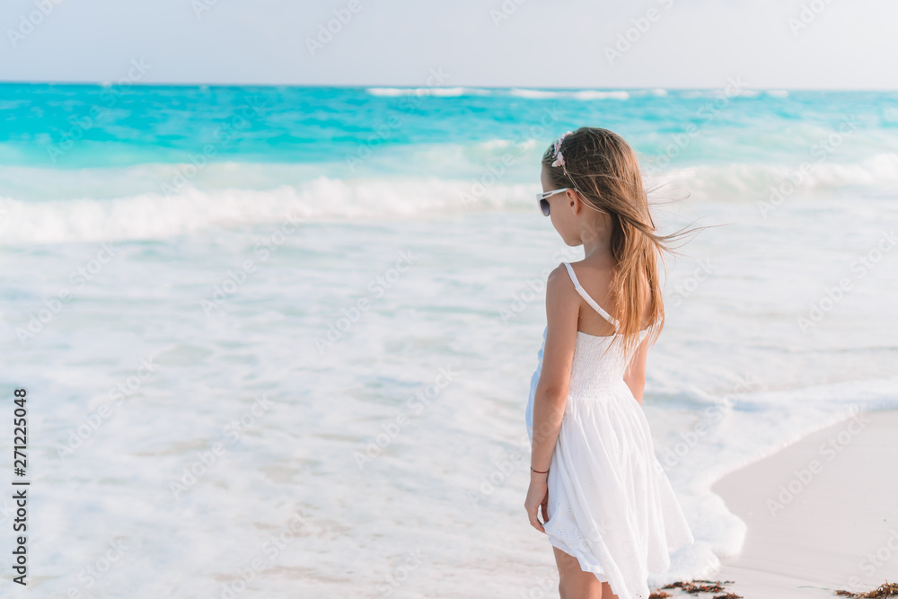 Adorable little girl at beach having a lot of fun in shallow water