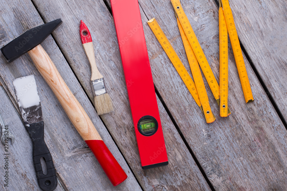 Repair tool kit background. Construction tools including palette-knife, hammer, paintbrush, spirit level and folding ruler on wooden background.