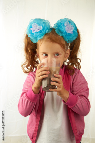 Girl drinking from a transparent glass of cocoa drink