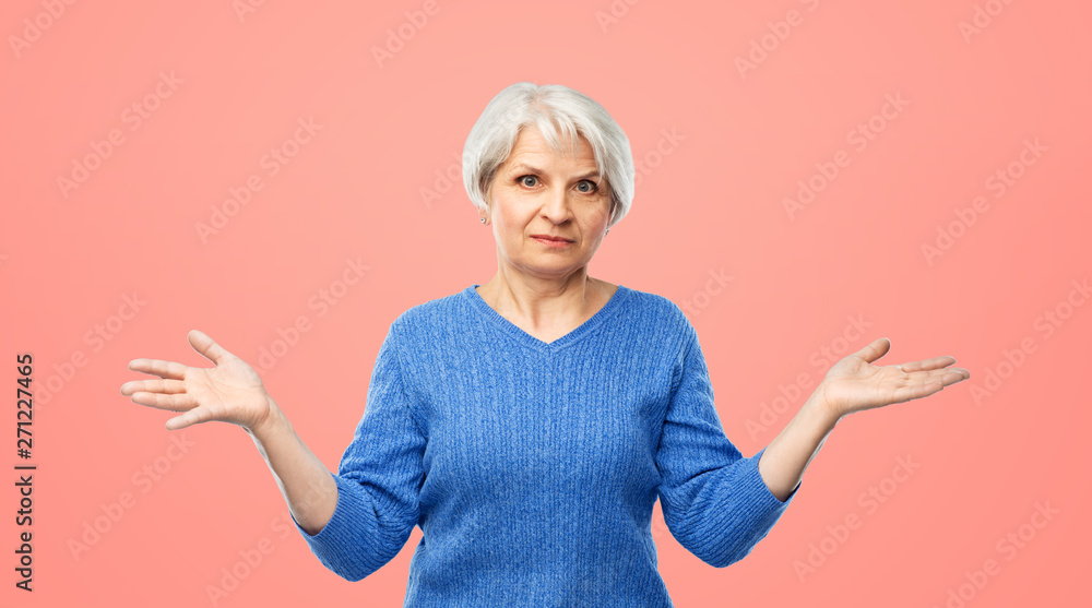 gesture, emotion and old people concept - portrait of senior woman in blue sweater having no idea and shrugging over pink or living coral background gesture, emotion and old people concept - portrait of senior woman in blue sweater having no idea and shrugging over pink or living coral background