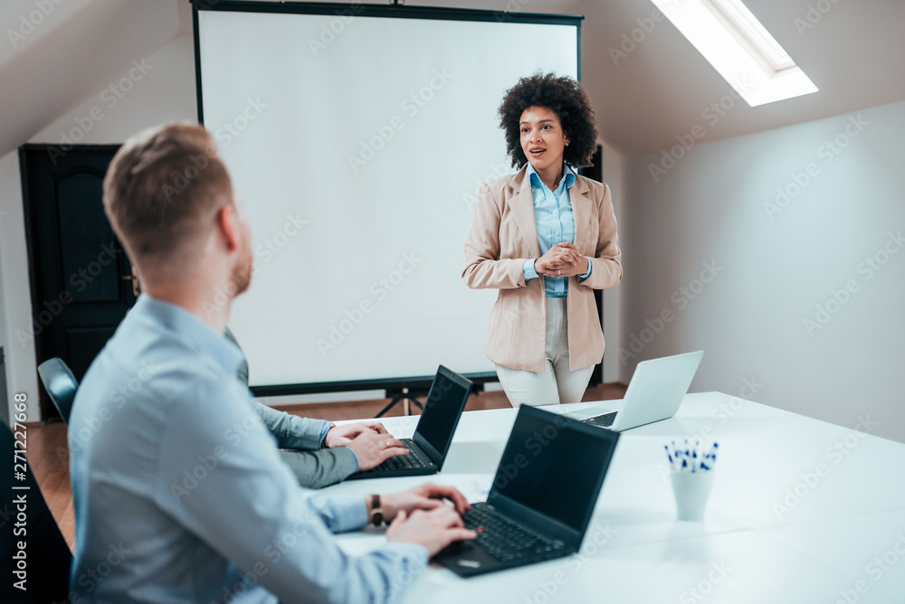 Young curly haired businesswoman presenting on a business meeting. Young curly haired businesswoman presenting on a business meeting.