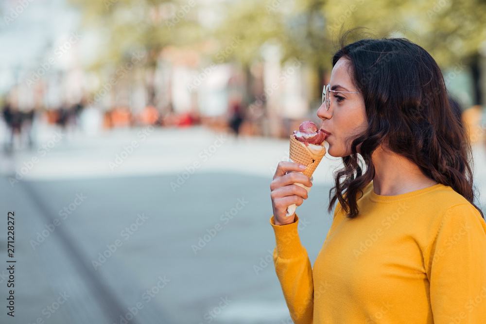 Young woman eating ice cream in the city street, copy space. Young woman eating ice cream in the city street, copy space.