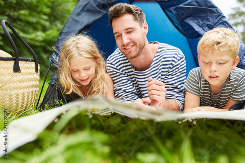Vater und zwei Kinder im Zelt beim Camping