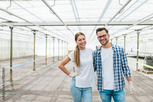 Portrait of a young couple of successful farmers at modern greenhouse.