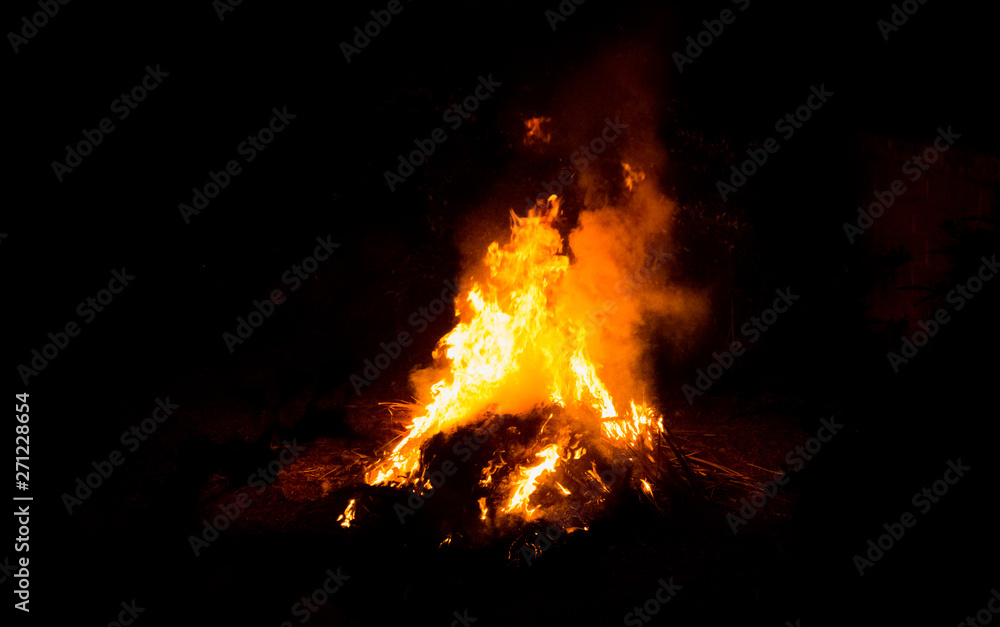 Large burning bonfire with soft glowing flame and sparkles flying all around