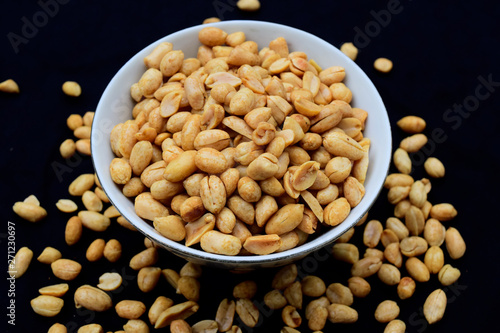 Salted fried peanuts on a plate with a blank black background.