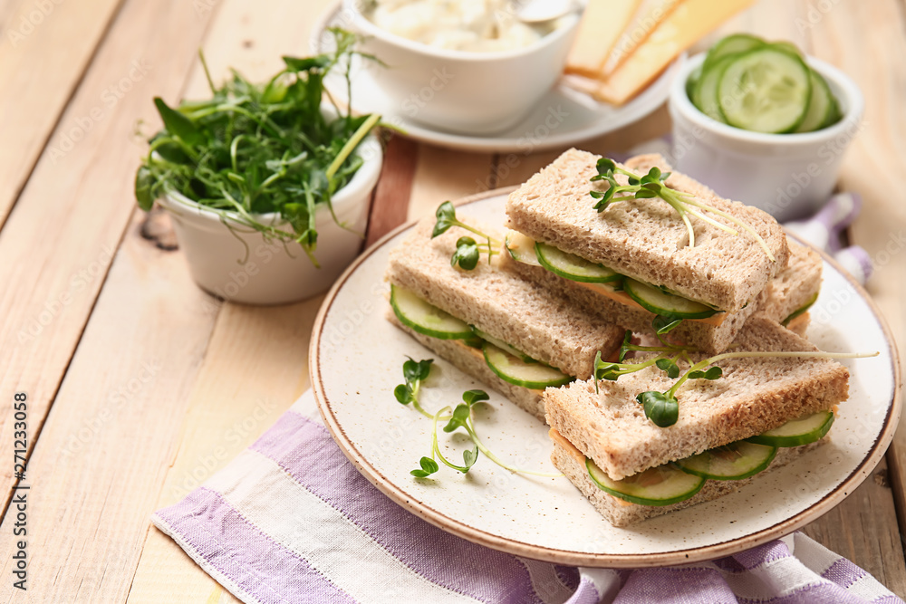 Plate with tasty cucumber sandwiches on wooden table Plate with tasty cucumber sandwiches on wooden table