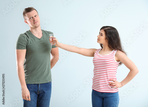 Young woman giving glass of...