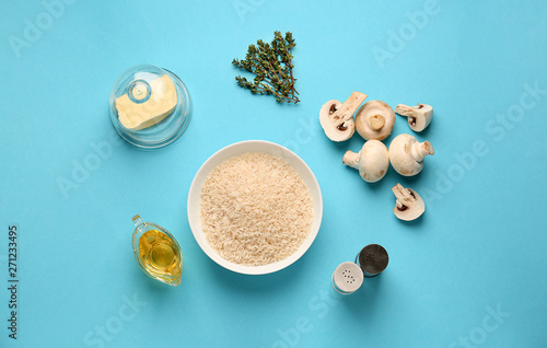 Raw ingredients for risotto on color background