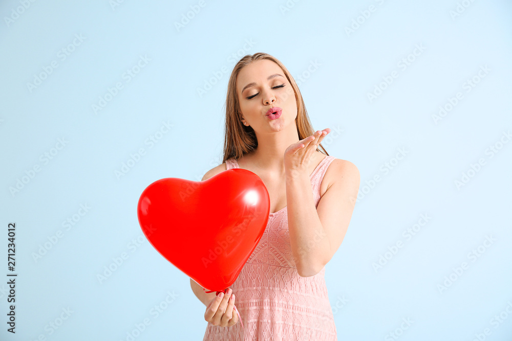 Beautiful young woman with heart-shaped air balloon blowing kiss on light background Beautiful young woman with heart-shaped air balloon blowing kiss on light background
