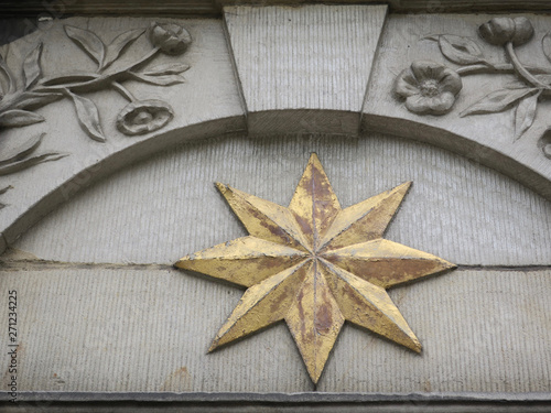Bilde på lerret golden star and flowers with leaves in freestone above a door