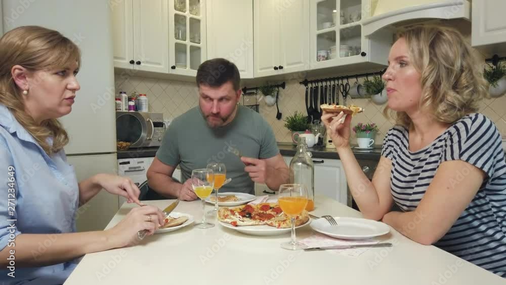 Adult friends eating pizza at the table Adult friends eating pizza at the table