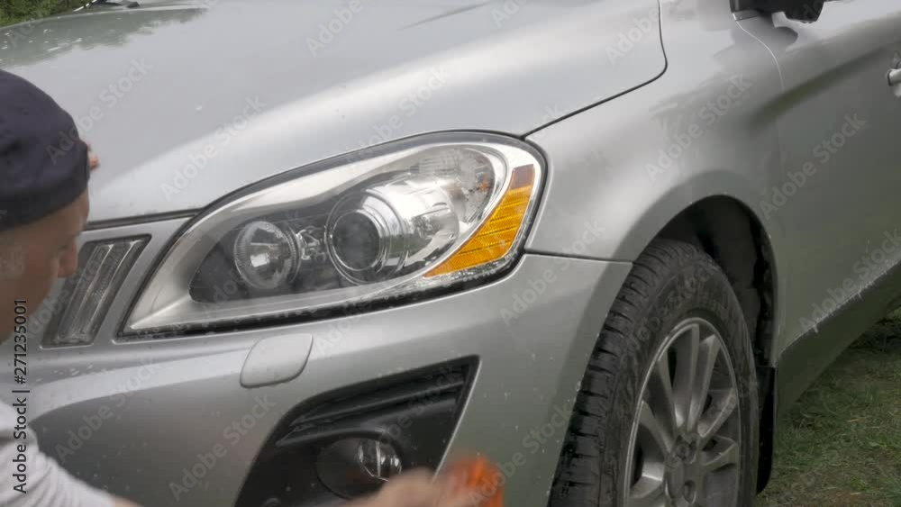 man holds sponge washes carefully grey hatchback headlights man holds sponge washes carefully grey hatchback headlights